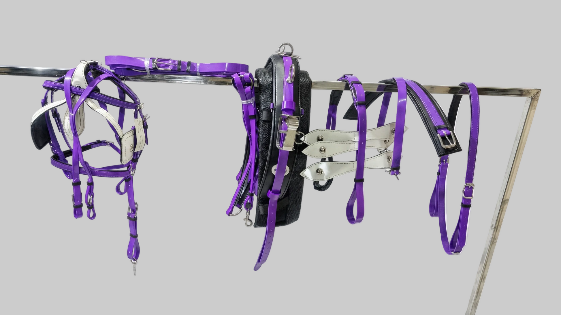 Purple equestrian bridle and reins on a stand against a white background